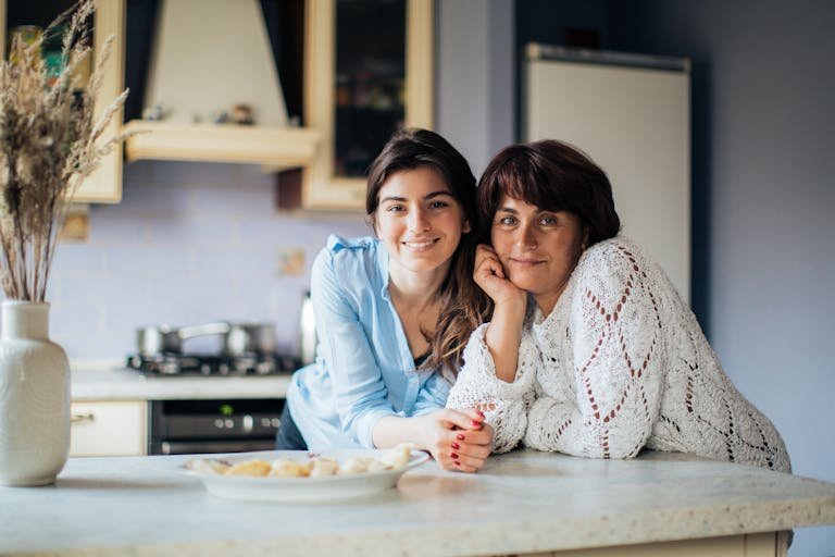 A mother and daughter bonding in the kitchen, smiling and enjoying their time together.
