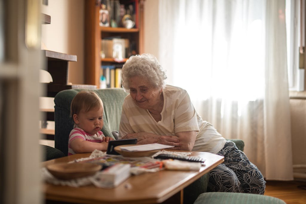 Elderly woman and baby enjoying together time indoors.