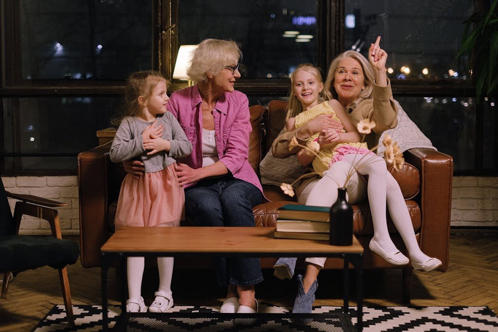 Two grandmothers enjoy quality time with their granddaughters indoors.